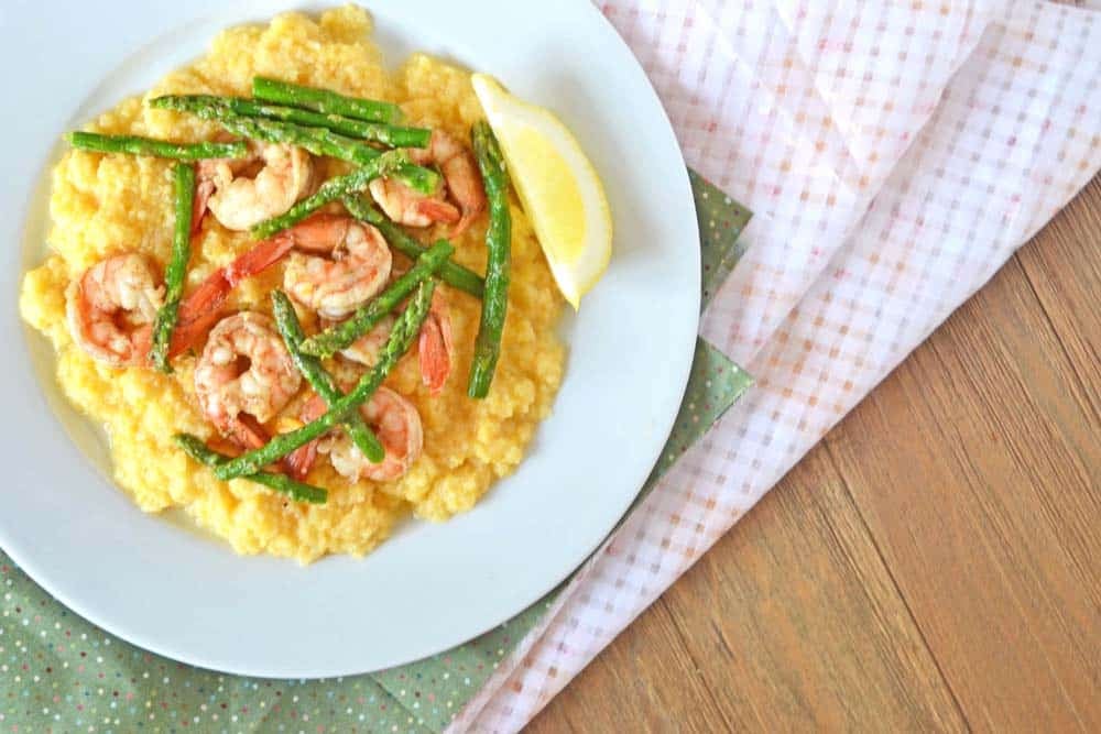 Shrimp and Polenta topped with asparagus, with a lemon wedge on the side.