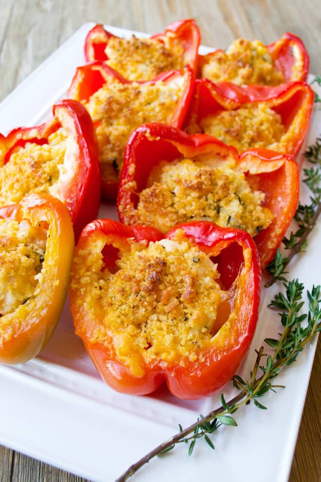 Red bell pepper halves stuffed with chicken and cheese and topped with panko breadcrumbs that are browned.