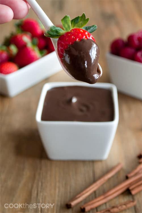 Dark Chocolate Greek Yogurt Fruit Dip in a white container and on a strawberry.