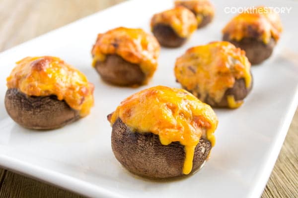 Chili-Stuffed Mushrooms topped with cheese on a white platter.