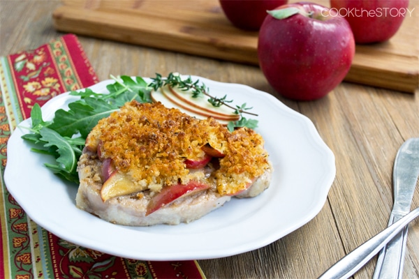 Pork chop with apple and cheddar on a plate.