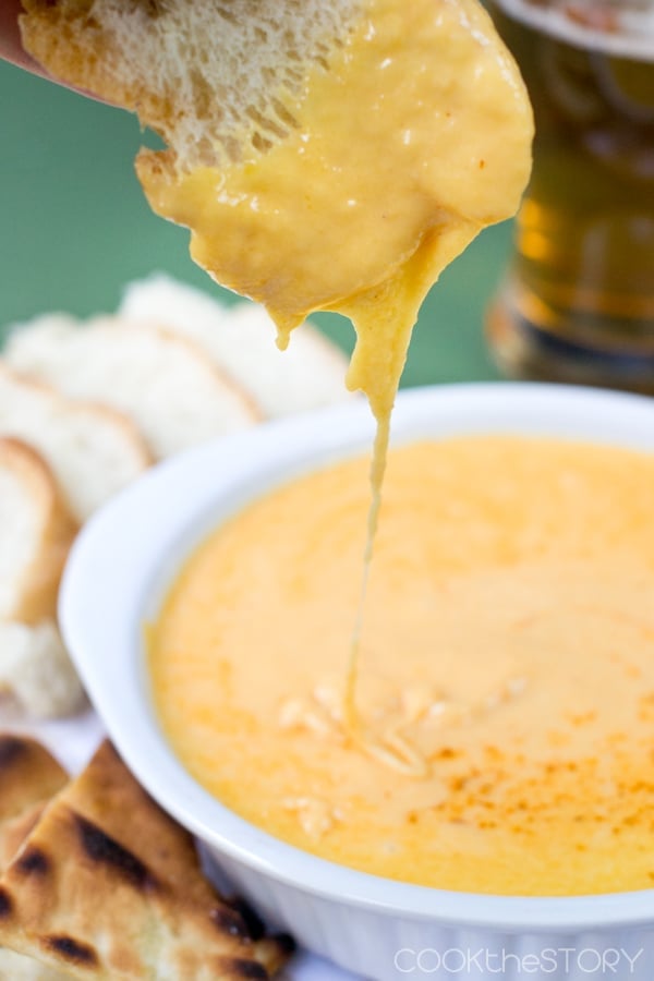 Bread being dipped into beer cheese dip.