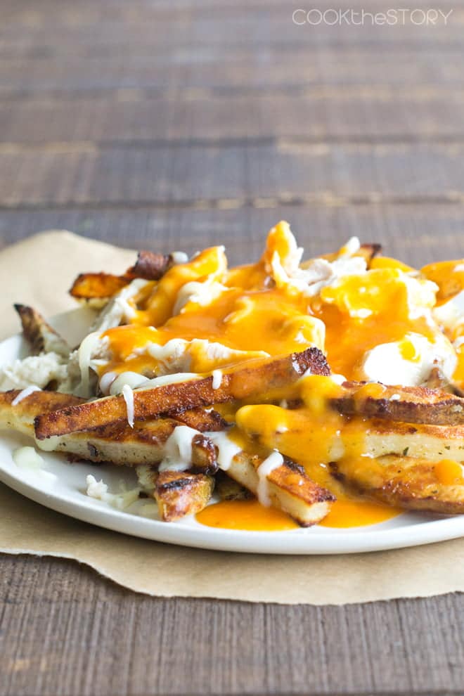 French fries covered in cheese and gravy on a white plate.