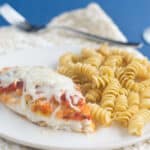 Fish Parmesan with rotini pasta on a white plate.