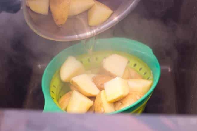 Draining potatoes into a colorful colander in the sink.