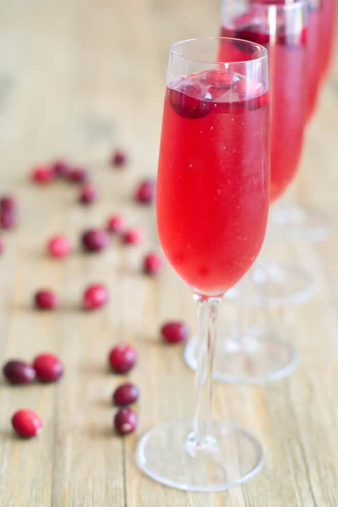 Champagne flutes with cranberry punch and fresh cranberries.