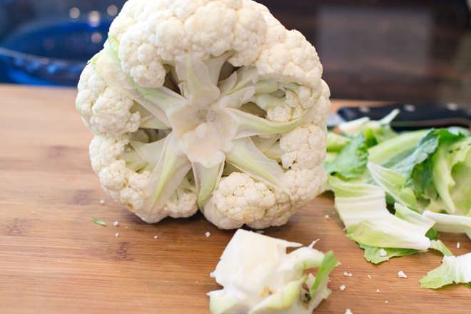 Head of cauliflower with leaves and core removed to the cutting board.