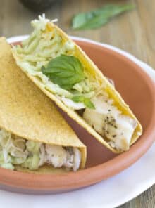 Two fish tacos on a terracotta plate