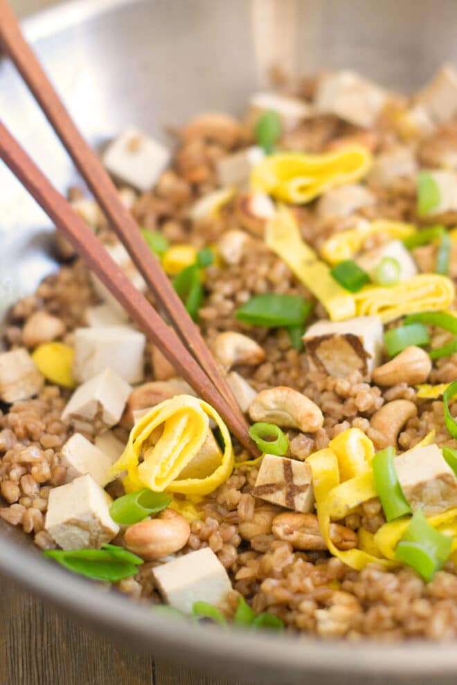 A wok with farro, egg, green onions and cashews
