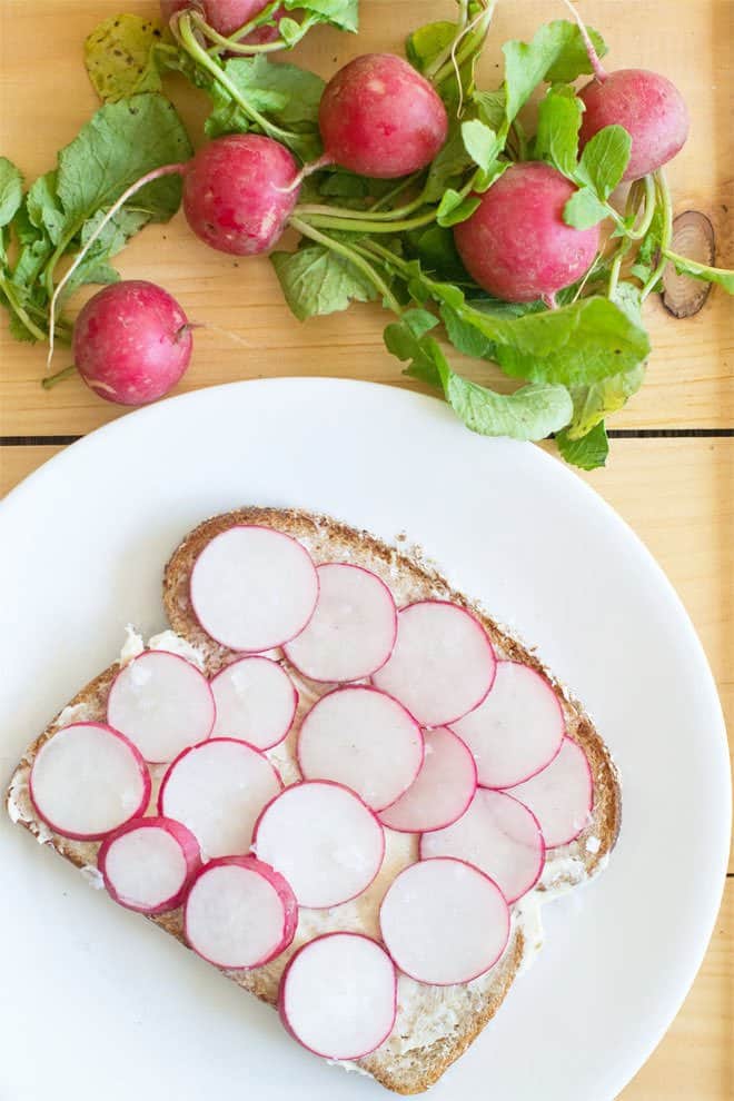 Slices of radish on a buttered slice of bread on a white plate.