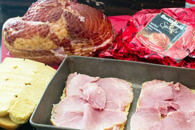 Slices of ham being put on rolls in baking pan.