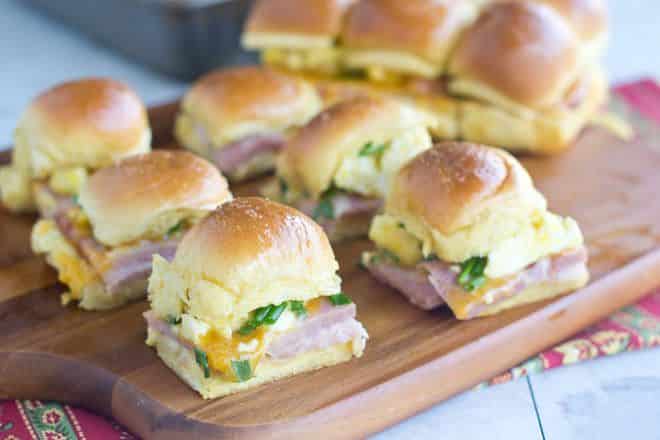 Find out how to make sliders for a crowd with zero fuss. These breakfast sliders are super easy to make because you start with a bunch of attached buns (the kind that are sold all attached to each other) and you build one quick big sandwich. Then you bake it. Once it's hot inside and toasty on top, you cut the buns apart into individual sliders. It's so so much easier than making a whole bunch of individual sliders. And they're delicious too!