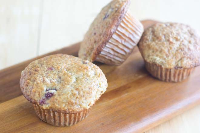 Three cranberry sauce muffins on a wooden board.