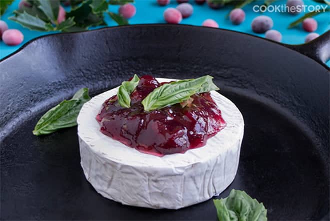 Brie wheel topped with jam and mint on a cast iron skillet.