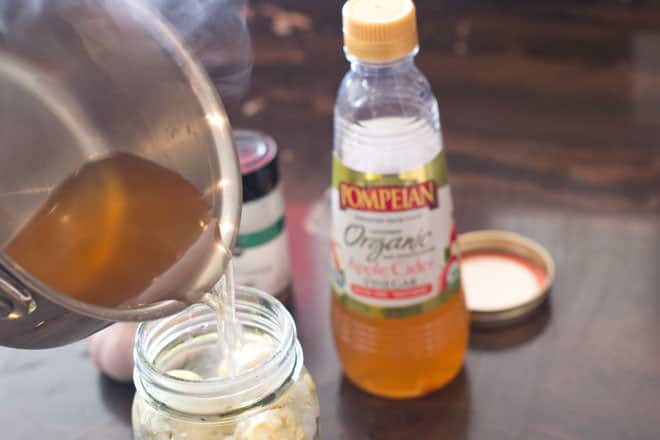Apple cider vinegar mixture being poured into the mason jar.