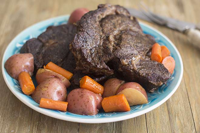 Finished pot roast with potatoes and carrots on a serving plate.