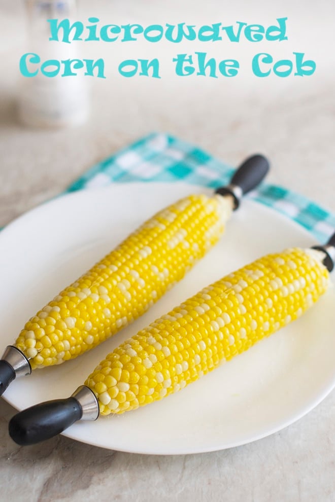 Two ears of white and yellow corn with cob holders on a white plate, text reads Microwaved Corn on the Cob.