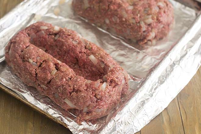 Meatloaf mixture shaped into loaves with a trench in the middle.
