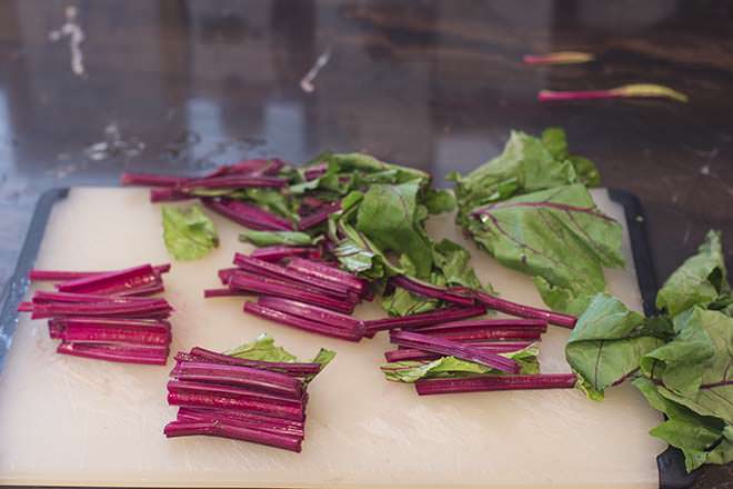 Beet stems and leaves on a cutting board, in two inch segments.