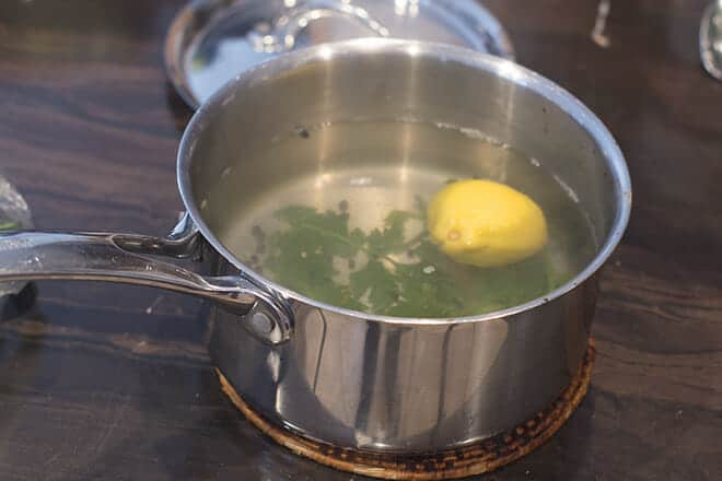 Hot saucepan of water and aromatics on a trivet on the counter.
