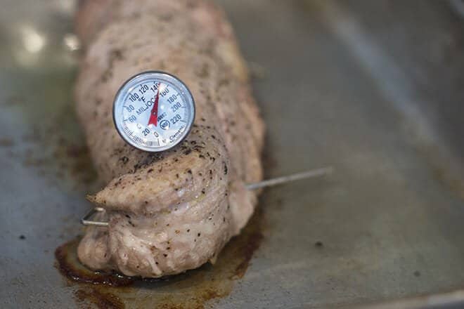 Cooking pork tenderloin with a meat thermometer stuck in it reading 145°F