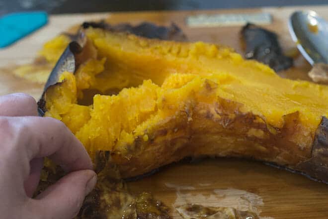 Peeling off the skin from a roasted butternut squash.