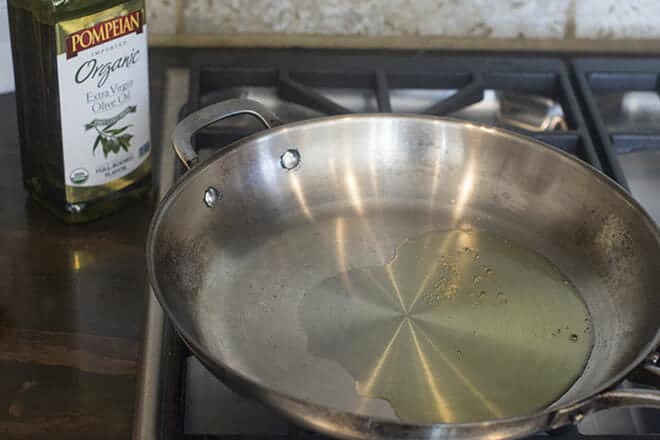 Olive oil being heated in a pan on the stove.