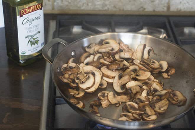 Mushrooms browning in a pan on the stove.
