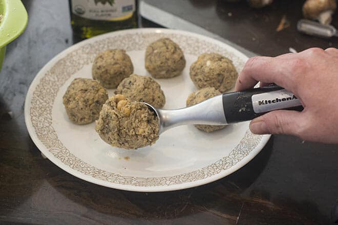 An ice cream scoop being used to form meatball mixture into balls.