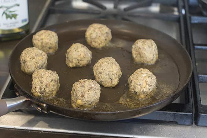 Vegan meatballs being cooked on a pan on the stove.