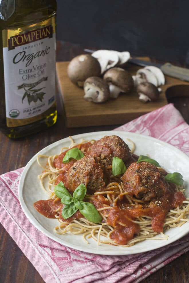 Vegan meatballs with spaghetti and sauce on a white plate.
