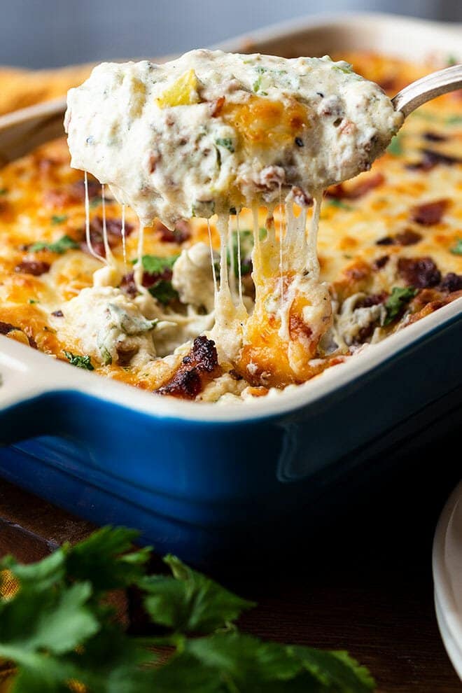 Spoonful of jalapeno popper dip over a blue casserole dish of dip.