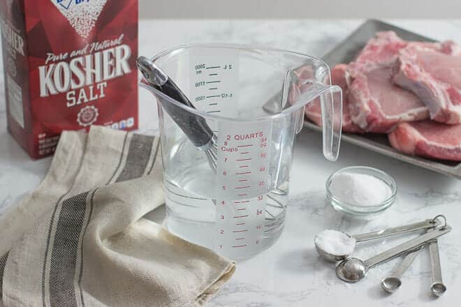 Measuring cup with whisk, salt and meat in background.