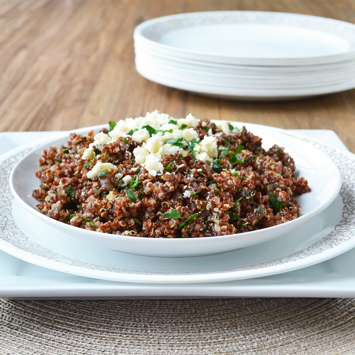 Red quinoa on a white dish topped with crumbled feta and parsley