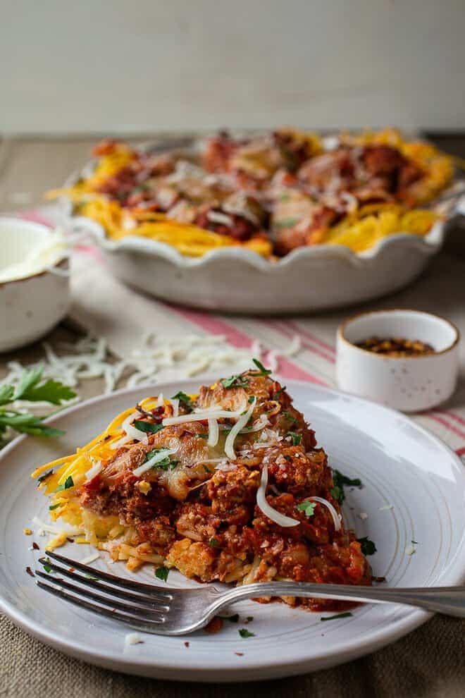 Slice of spaghetti pie on plate with fork. 