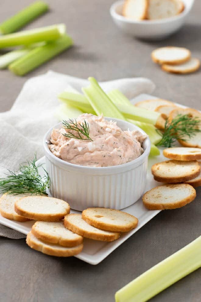 White ramekin with smoked salmon dip surrounded by toast rounds.