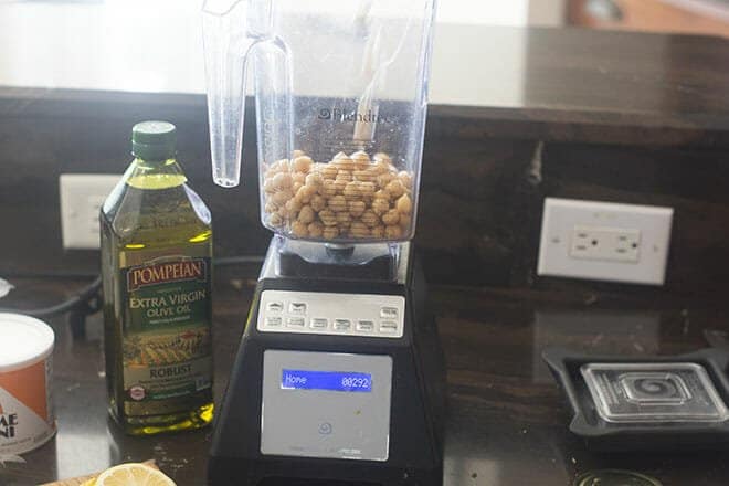 Chickpeas in a blender, with olive oil next to it.