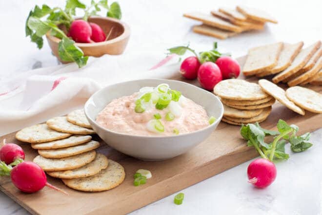 Salmon Dip on a tray with crackers and mini radishes.
