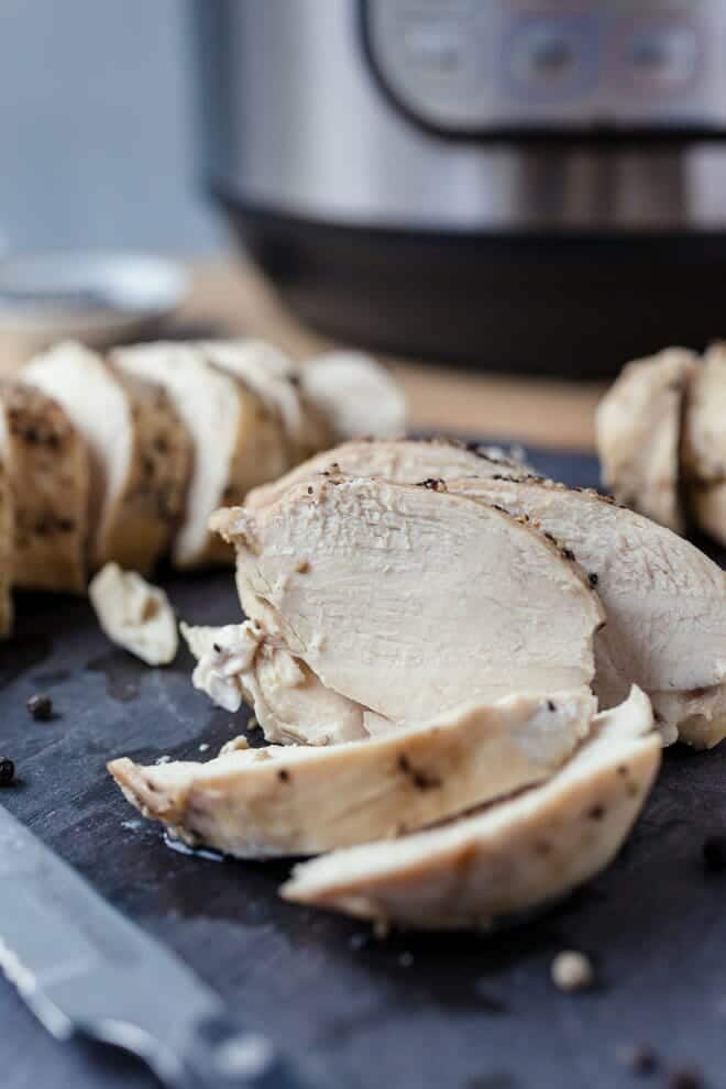 Sliced chicken breast in front of an instant pot.