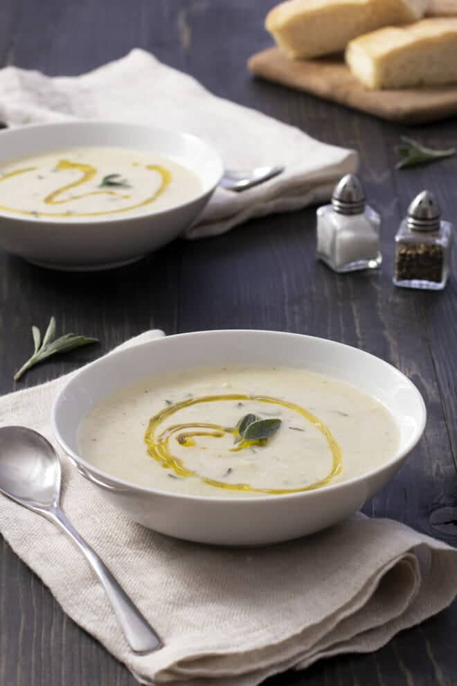 White bowl of cauliflower soup with swirl of olive oil.