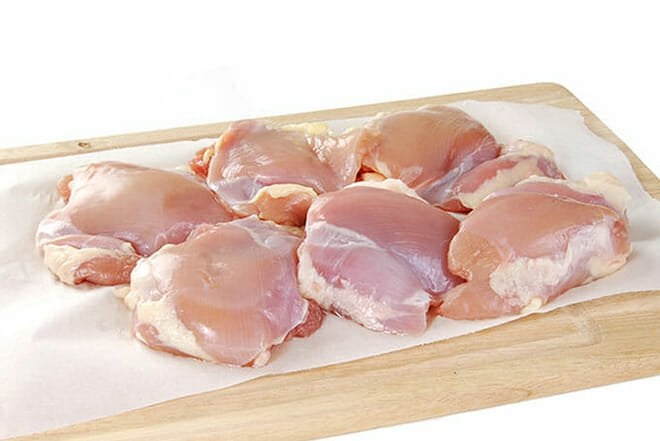 Raw chicken thighs on a cutting board.
