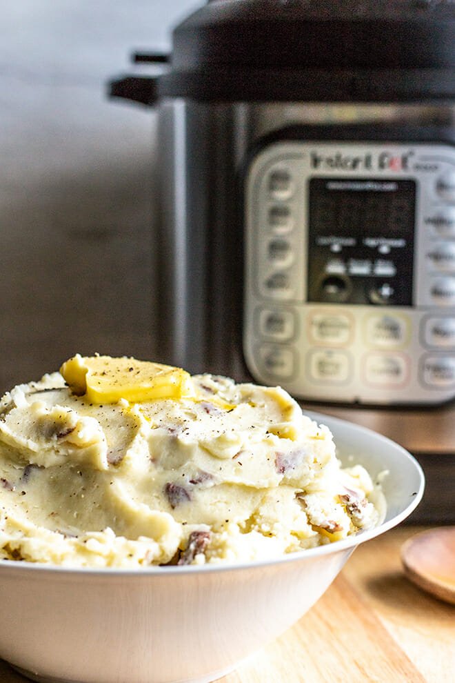 White bowl of mashed potatoes in front of Instant Pot.