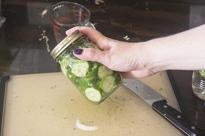Glass jar of quick pickles being shaken.