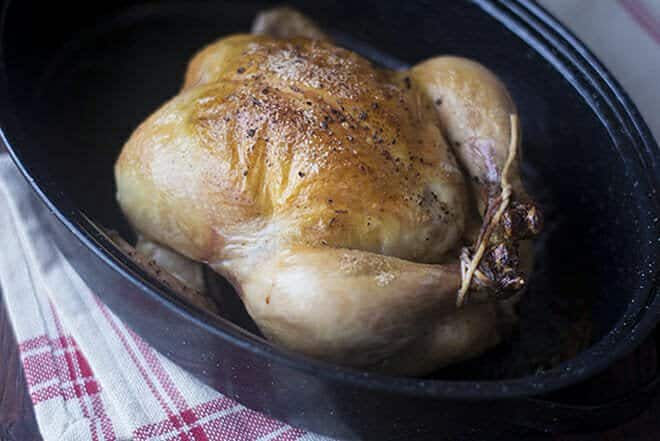 Whole roast chicken in roasting pan.