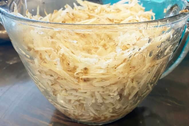Shredded potatoes in a large measuring cup showing that you need 6 cups but a bit more is fine, there is a bit over 6 cups here.