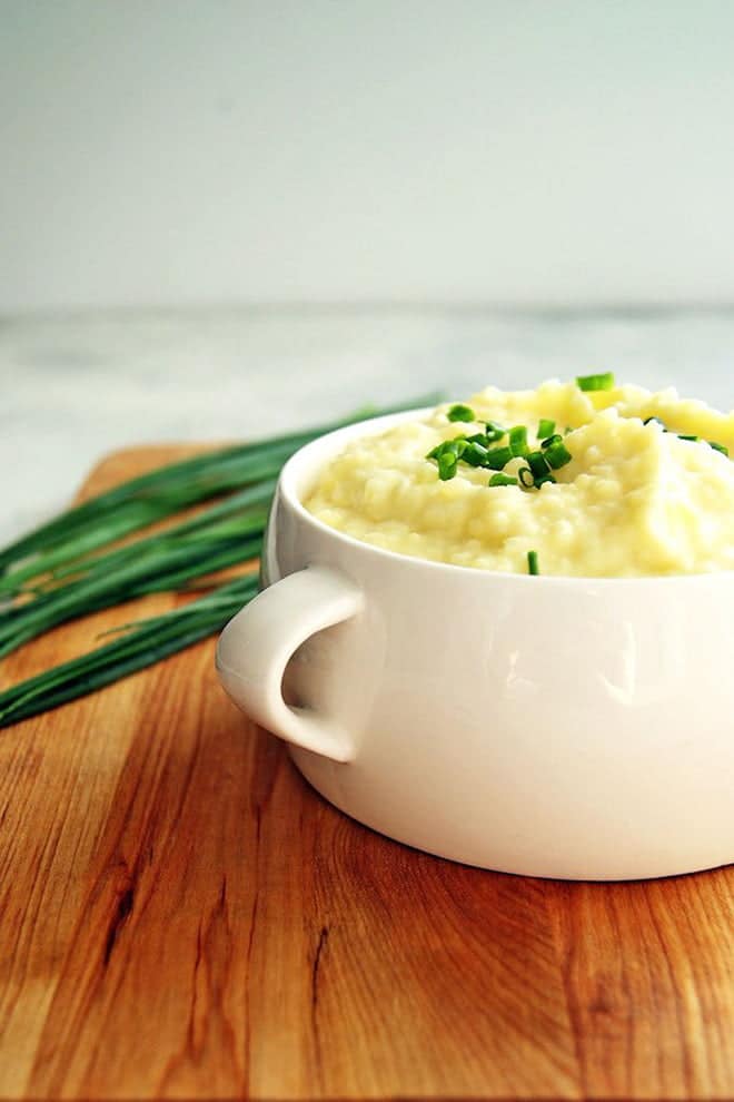 White dish with mashed potatoes topped with scallions.