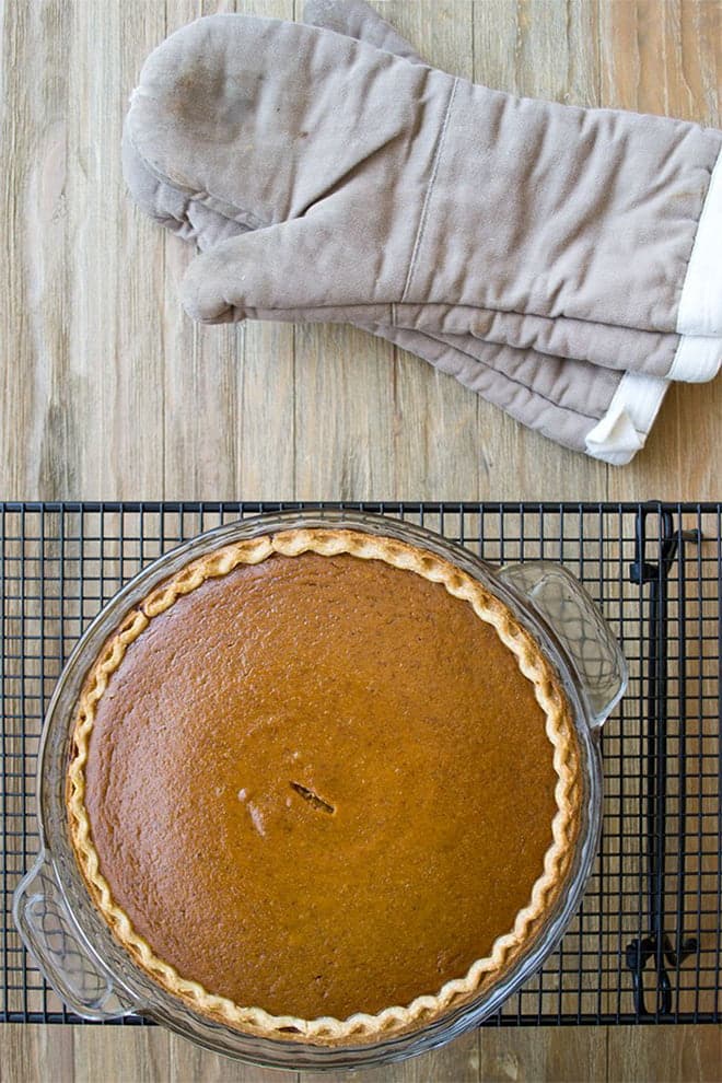 Pumpkin pie in a glass pie dish on a cooling rack.