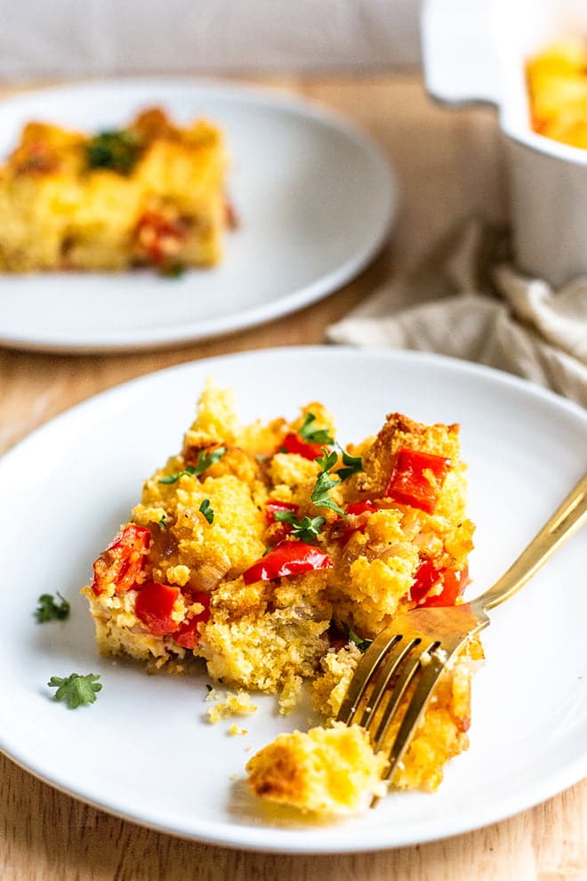 Cornbread Casserole with red peppers on a white plate with fork.