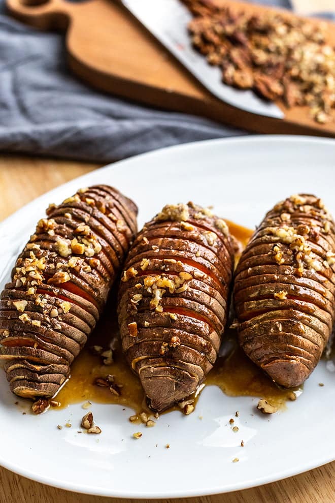 Hasselback Sweet Potatoes with brown sugar pecan glaze on a white plate.