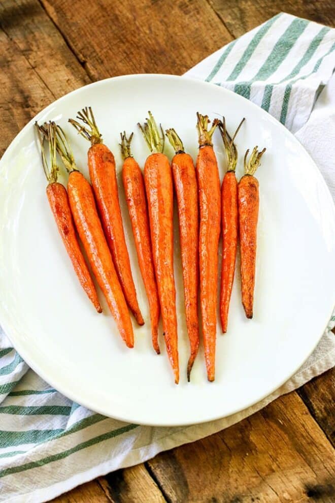 Whole roasted carrots on a white plate.